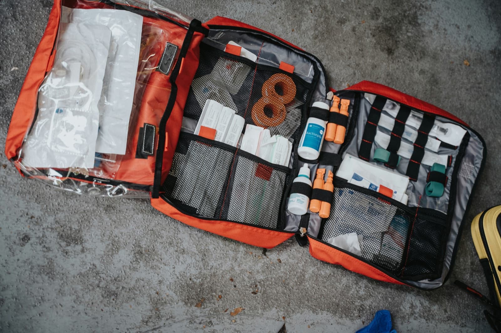 Öppen orange sjukvårdsryggsäck med förband och medicinsk utrustning i fack, uppifrån
