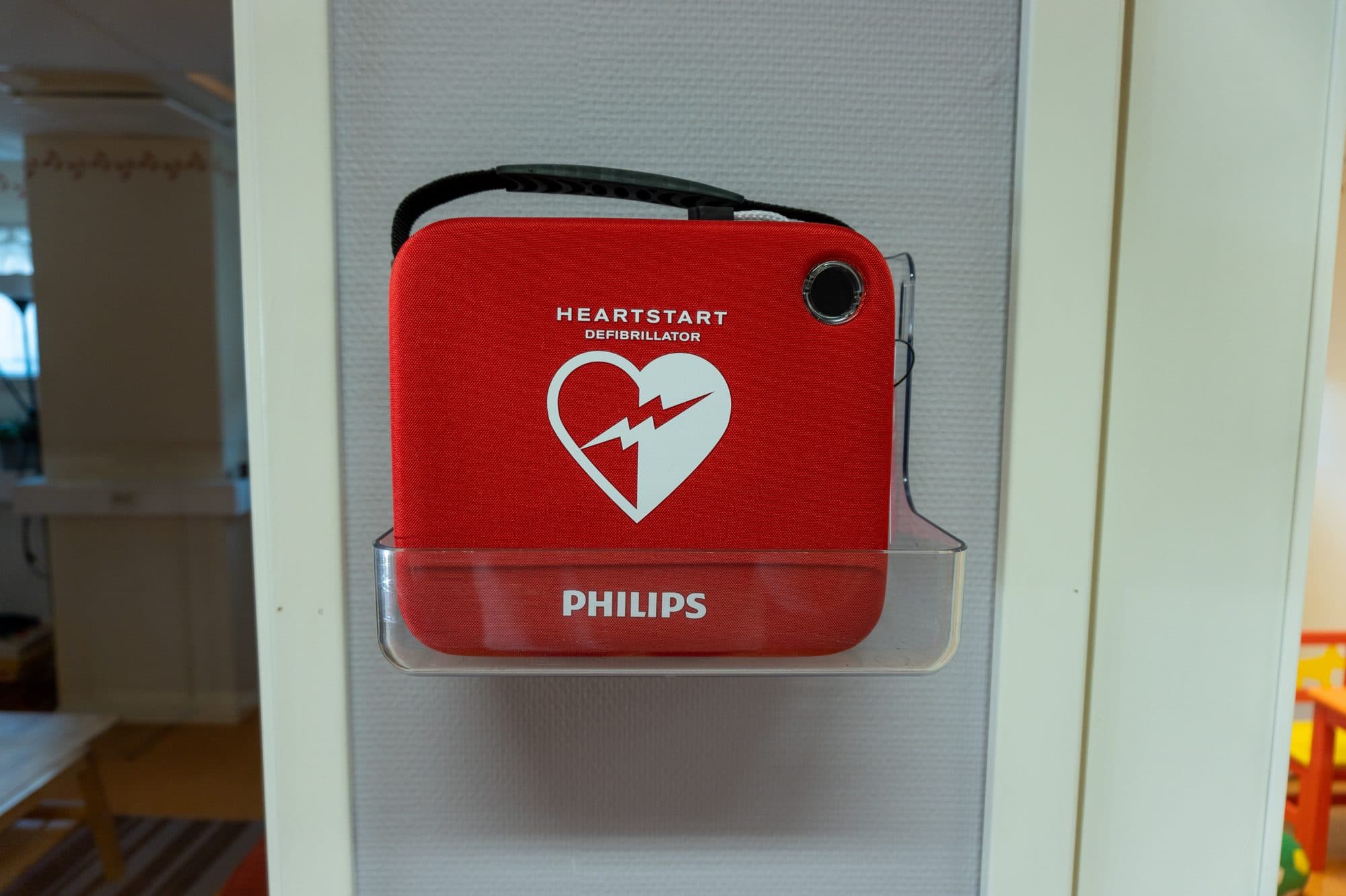 Röd Philips-hjärtstartare i väggfäste i en ljus korridor