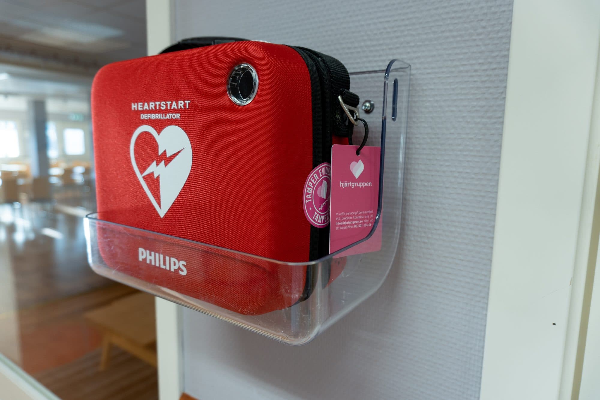 Röd Philips-hjärtstartare i ett väggfäste av genomskinlig plast
