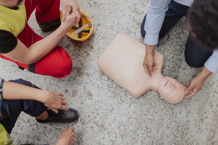 Sett uppifrån knäböjer flera personer runt en HLR-docka och övar hjärtkompressioner