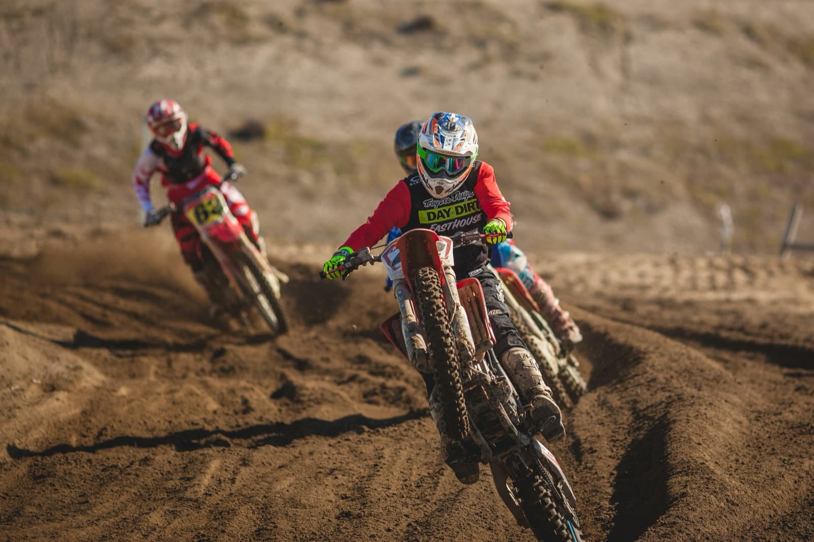Motocrossförare i full fart genom en sandig kurva under en tävling