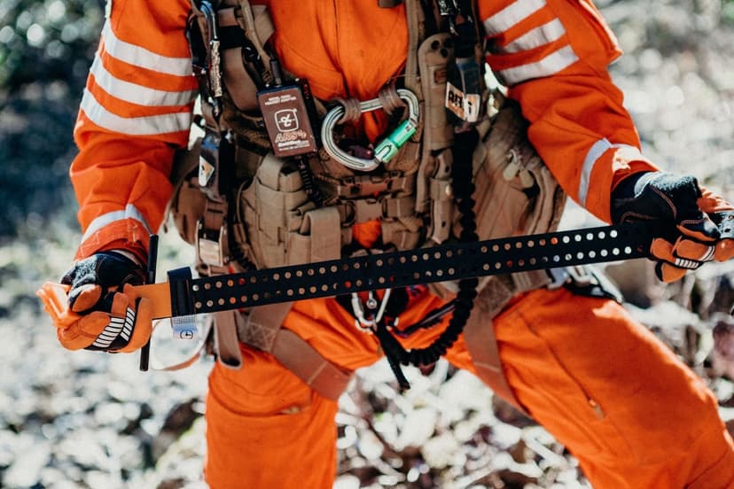 Närbild på en person i orange skyddsdräkt som håller en svart tourniquet med händerna