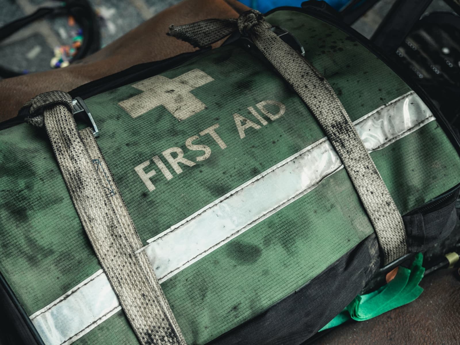 Närbild på en sliten grön väska med texten First Aid