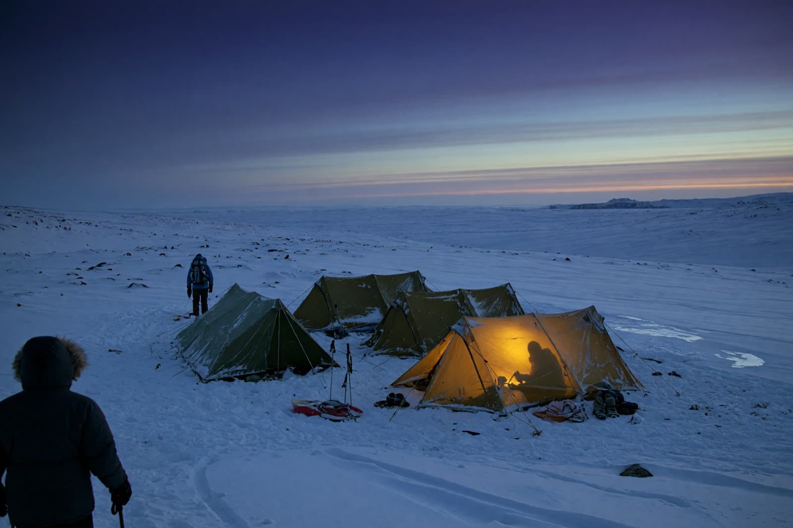 Expeditionstält på en snötäckt högplatå i skymningen